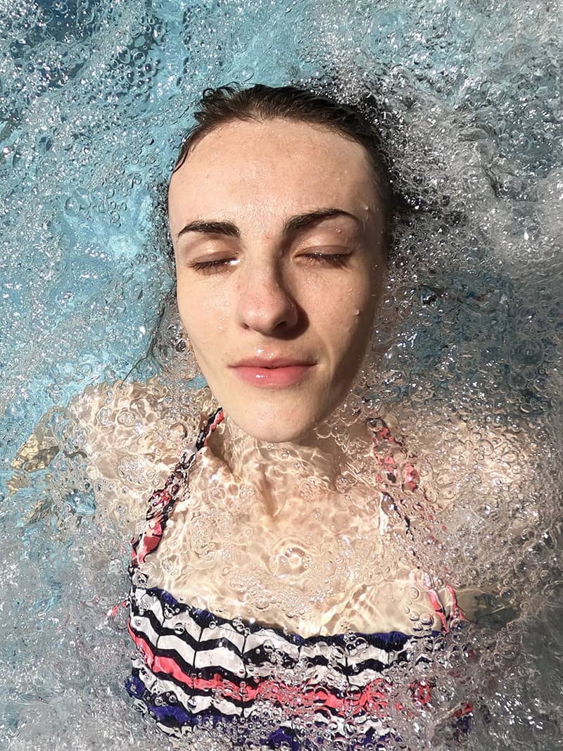 woman relaxing in hydro pool bubbles warm water with sun on her face