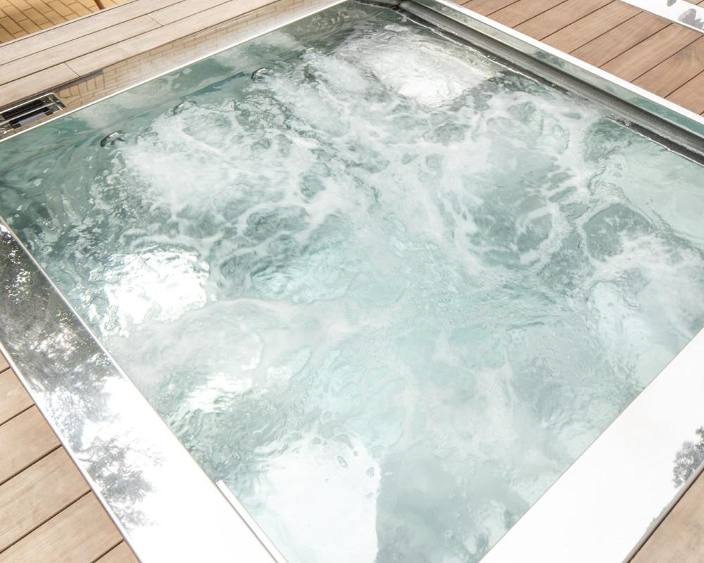 Stainless steel hot tub with water jets on - set in UK outdoor private garden