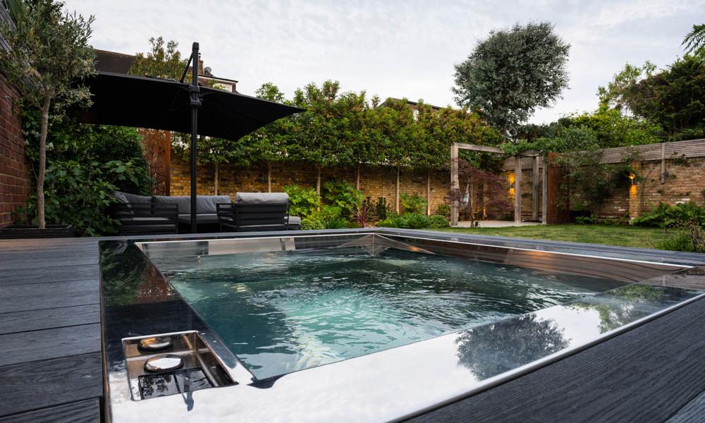 stainless steel hot tub with low water jets set in private, tree-lined garden